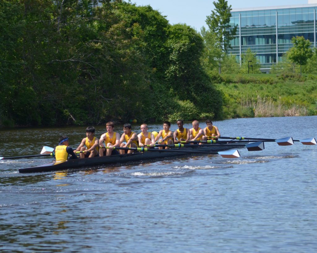 A group of people rowing in a boat on the water.