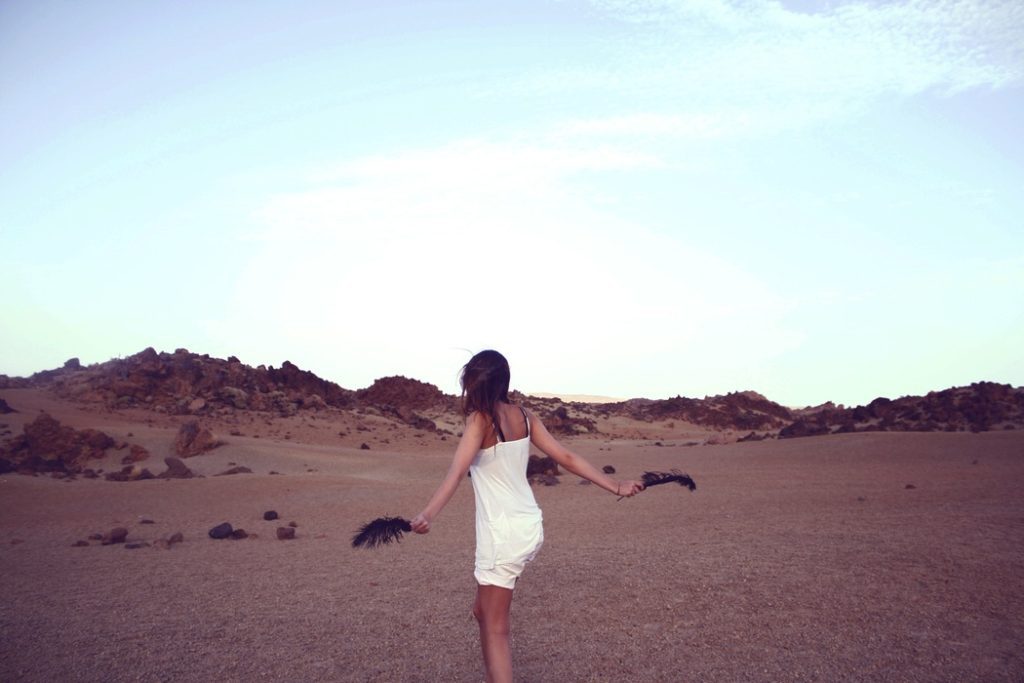 A woman in white dress standing on top of a sandy beach.