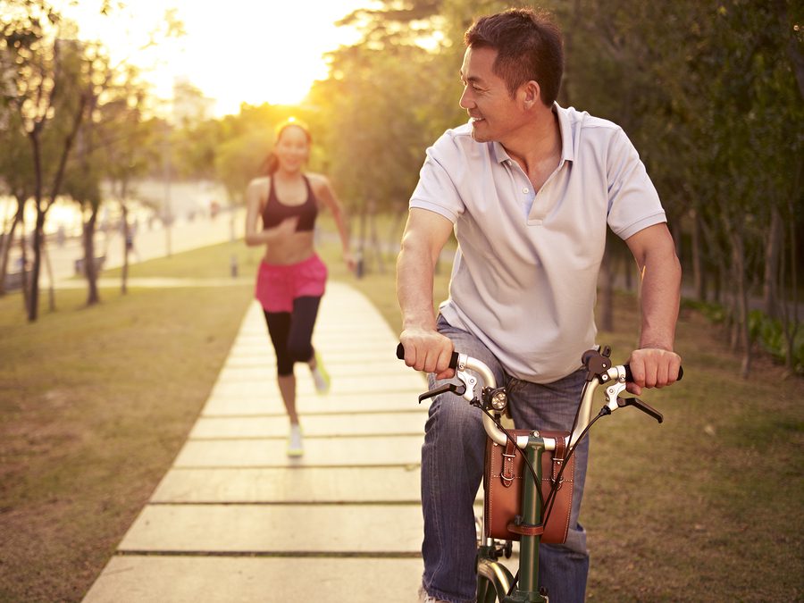 A man riding on the back of a bike next to a woman.