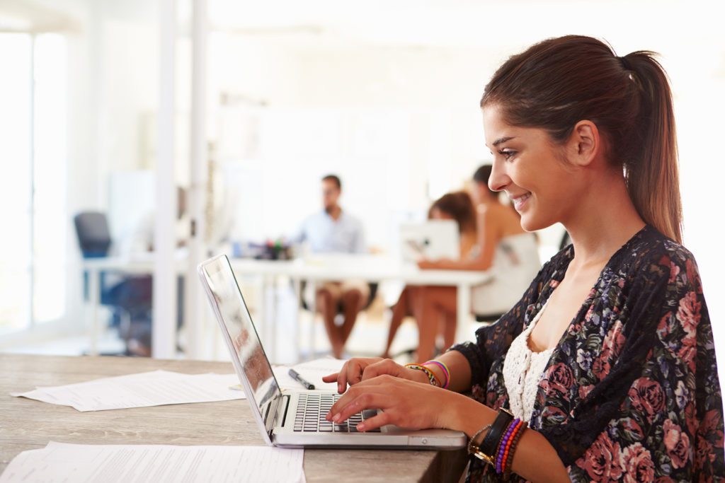 A woman sitting at a table using her laptop.