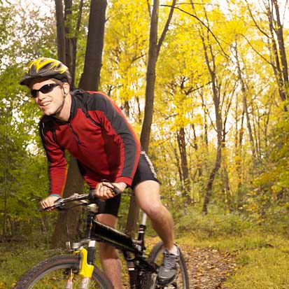 A man riding his bike through the woods.