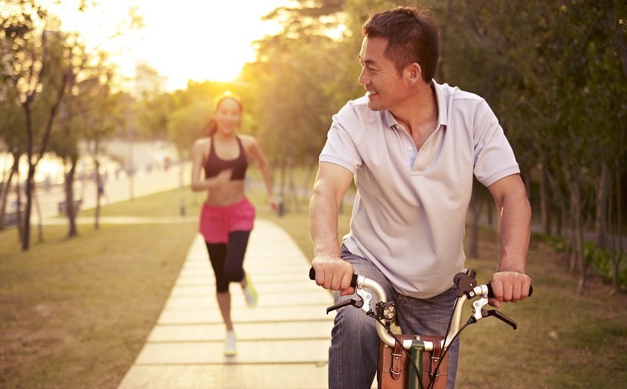 A man riding a bike next to a woman running.