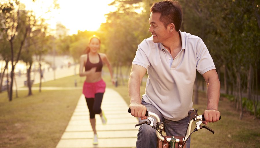 A man riding a bike next to a woman running.
