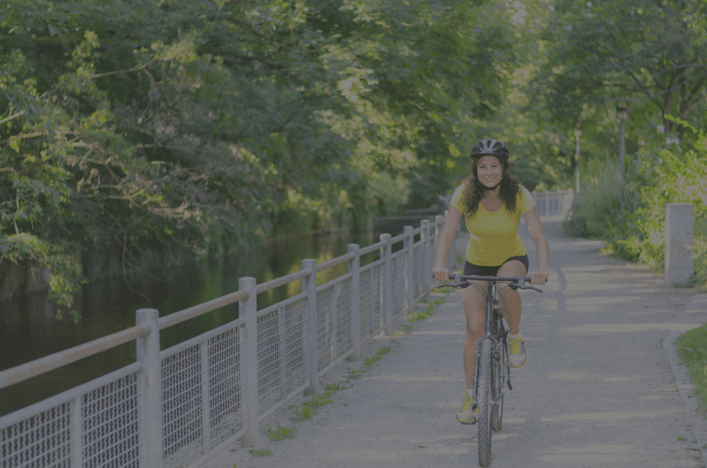 A woman riding her bike on the side of a river.