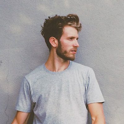 A man with a beard and mustache wearing a gray shirt.