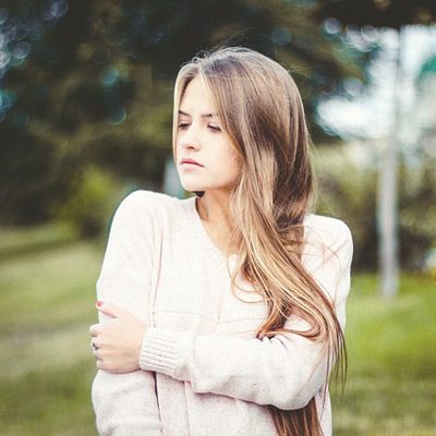 A woman with long hair is standing in the grass.