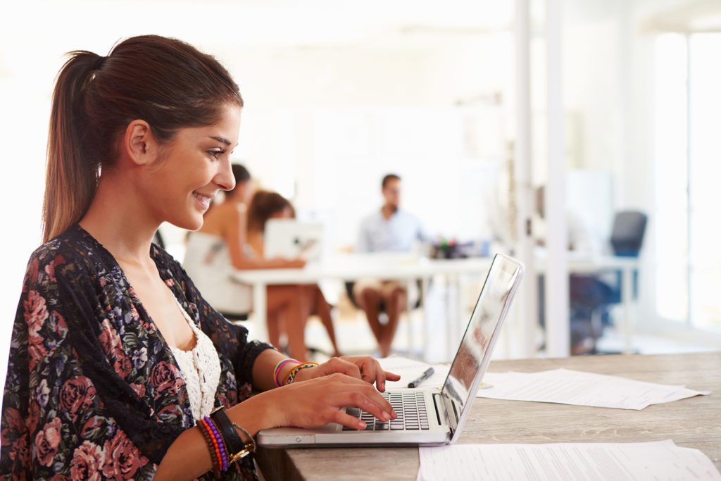 A woman sitting at a table using her laptop.