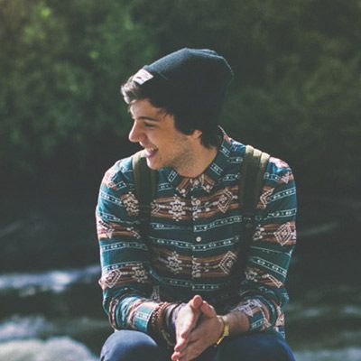 A man sitting on the ground near some water.