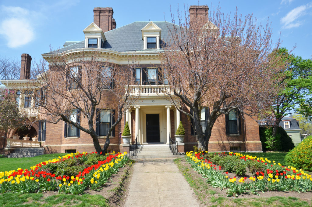 A large brick house with flowers in the front yard.