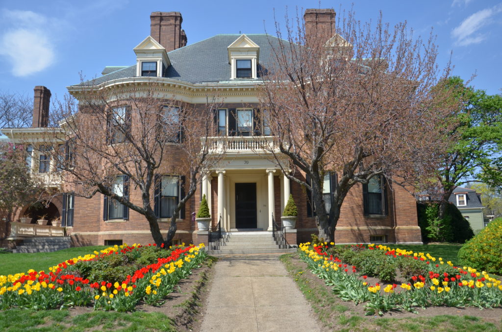 A large brick house with flowers in the front yard.