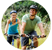 A man and woman riding bikes through the grass.