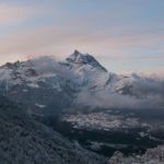 A mountain with snow on it and clouds in the sky.