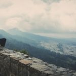 A person sitting on top of a stone wall.