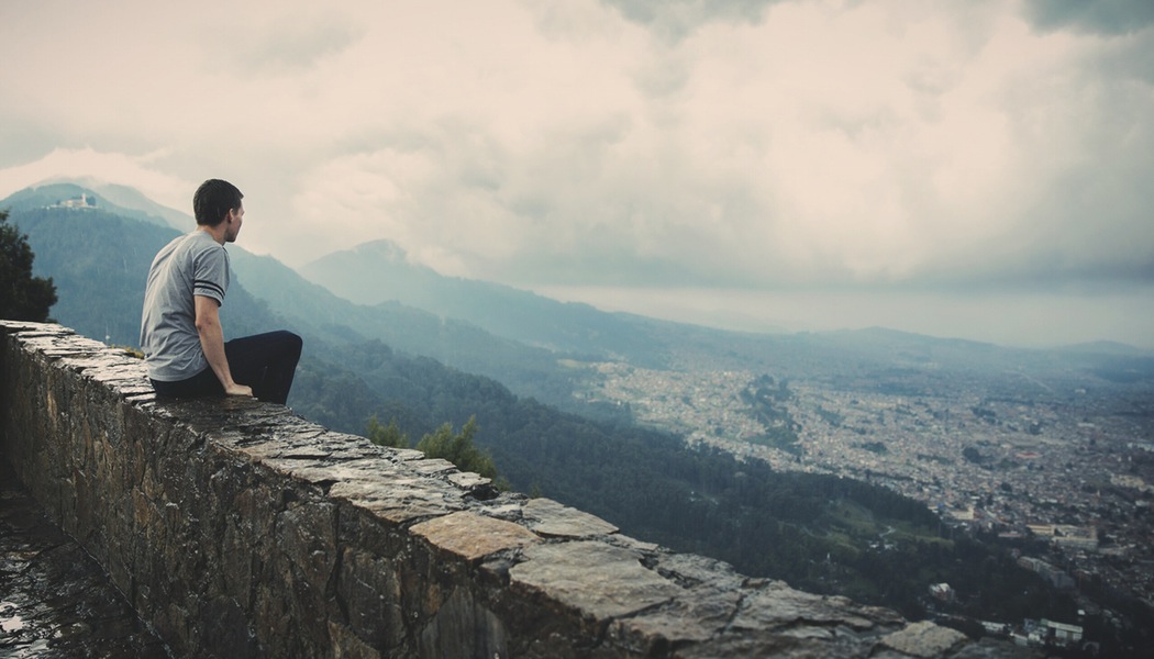 A person sitting on top of a stone wall.