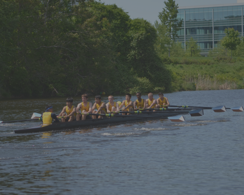 A group of people rowing in a boat on the water.