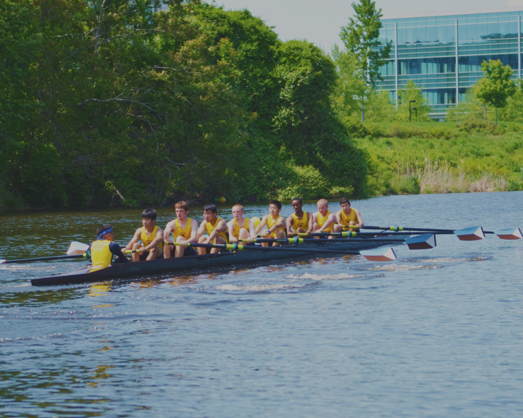 A group of people rowing in a boat on the water.