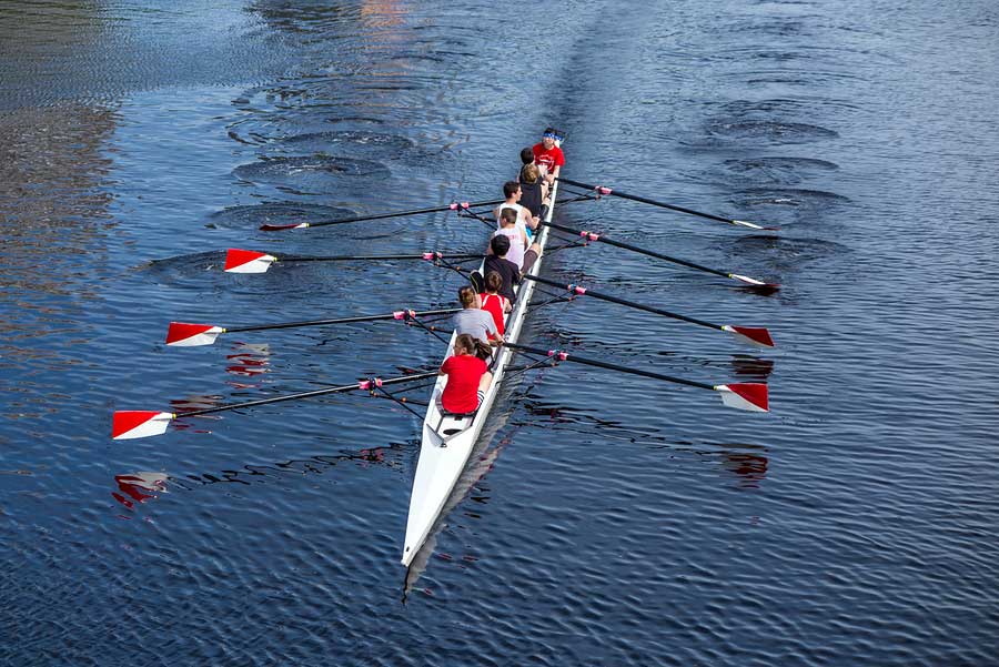 A group of people rowing in a boat on the water.