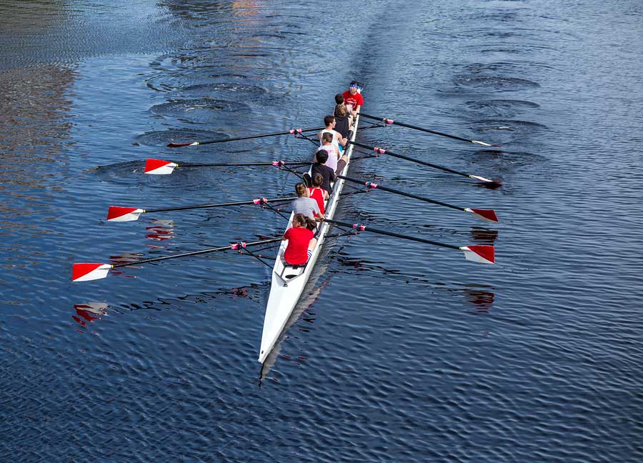 A group of people rowing in a boat on the water.