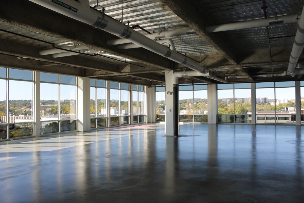 A large empty room with windows and concrete floors.