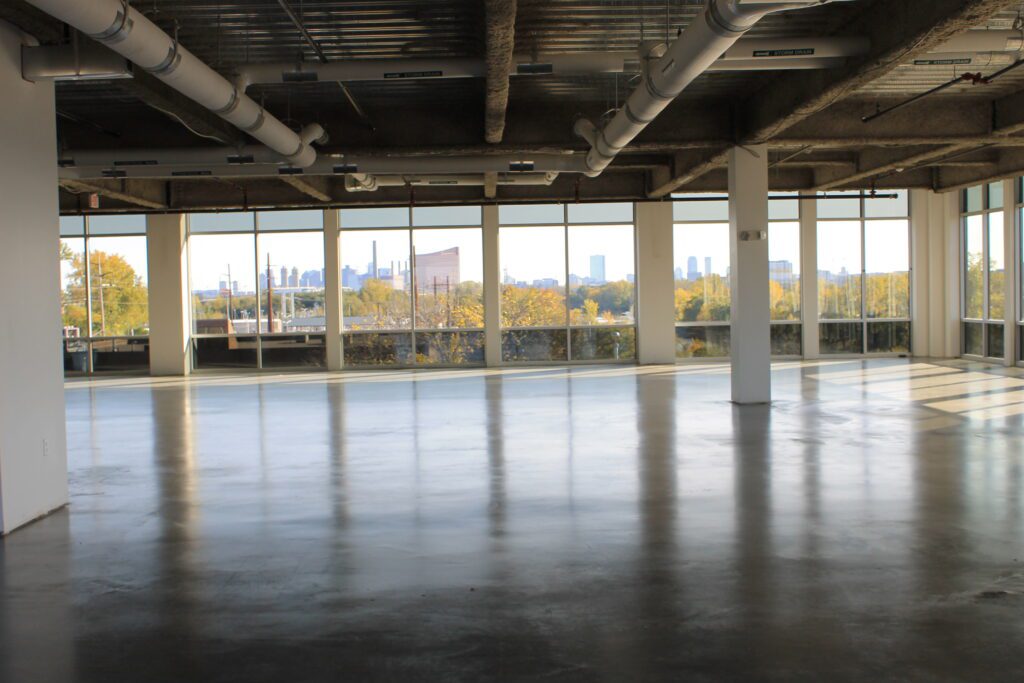 A large empty room with windows and concrete floors.