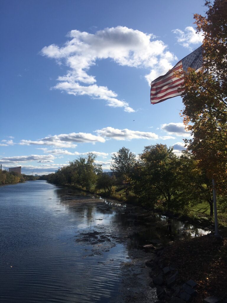 A flag flying over the water on a sunny day.